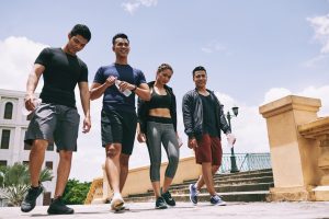 Cheerful Asian young people walking in the street after training and drinking water after